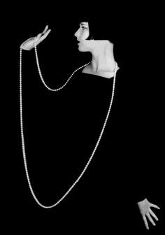 a black and white photo of a woman with her hands in the air while wearing a chain