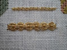 two pieces of gold chain sitting next to each other on a piece of white fabric