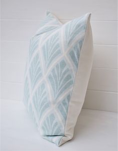 a blue and white pillow sitting on top of a white floor next to a wall