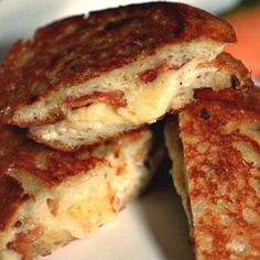 two grilled cheese sandwiches stacked on top of each other with fruit in the background