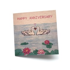 a happy anniversary card with two swans floating on water