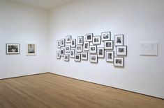 an empty room with several framed photographs on the wall and wooden floors in front of it