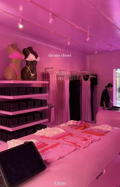 a woman's clothing store with mannequins and pink lighting