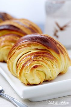 two croissants on a white plate next to a cup