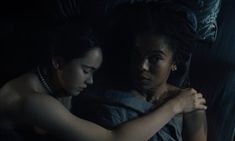 two women in the dark with their arms wrapped around each other and looking at something