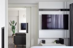 a living room with a flat screen tv mounted on the wall next to a bed