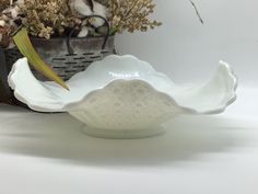 a white bowl sitting on top of a table next to a basket filled with flowers