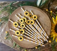 several yellow and white strawberries are arranged on a plate next to sunflowers