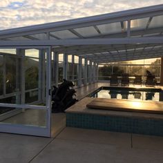 the inside of a house with a swimming pool and sun shining through glass doors on it