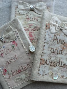 three embroidered cloths with words and flowers on them, one has a bow tie