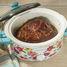 a crock pot filled with food sitting on top of a wooden table next to utensils