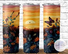 three vases with painted flowers and butterflies in front of a brick wall, on a wooden table