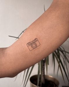 a person's arm with a camera tattoo on the left side of their arm