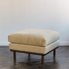 a foot stool sitting on top of a hard wood floor next to a white wall