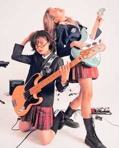 two girls in school uniforms are holding guitars