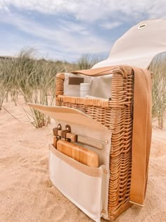 a wicker picnic basket with utensils in the sand