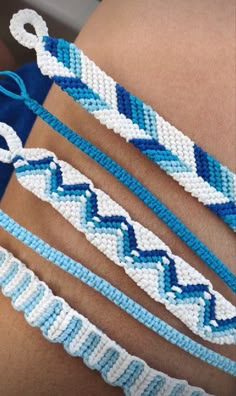 three bracelets with blue and white beads on the arm, one is made out of string