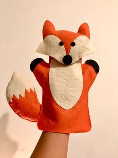 a hand is holding up a felt fox