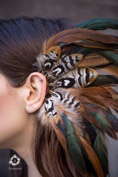 a woman with feathers in her hair is wearing an ear cuff made from real feathers