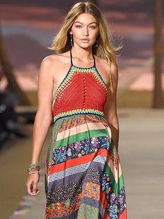 a model walks down the runway in a colorful dress