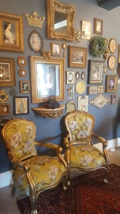 two chairs sitting in front of a wall with pictures on it