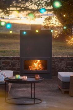 a fire place sitting in the middle of a patio next to a table with candles on it