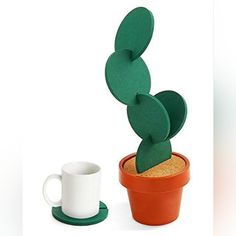 a cactus in a pot next to a coffee cup on a saucer and coaster