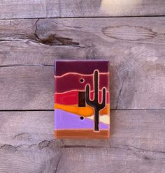 a tile with a cactus on it sitting on a wooden floor next to a wall