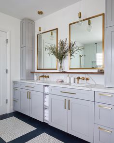 a bathroom with two sinks, mirrors and rugs on the floor in front of it