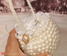 a hand holding a white purse with pearls on it