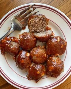 a white plate topped with meatballs covered in sauce next to a fork and knife