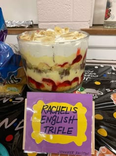 a trifle is sitting on a table next to a sign that says rachel's english triple