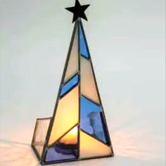 a stained glass christmas tree lamp with a star on it's top is shown in front of a white background