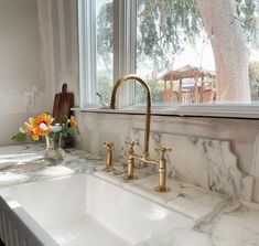 a kitchen with marble counter tops and gold faucets on the windowsills