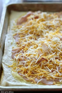 an uncooked pizza topped with cheese and ham