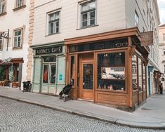 an empty street with shops and people walking on the side walk in front of them