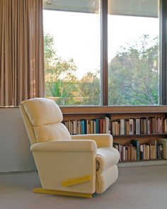 a white recliner chair sitting in front of a book shelf filled with lots of books