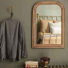 a room with a mirror, coat rack and books on the shelf next to it