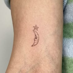 a small crescent moon and star tattoo on the right side of the arm