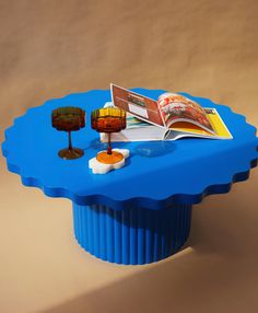 a blue table with a book on it and two lamps sitting on top of it