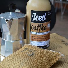 a bottle of iced coffee sitting on top of a wooden table next to a bag