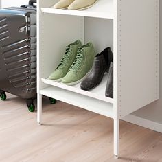 several pairs of shoes sitting on top of a white shelf next to a black suitcase