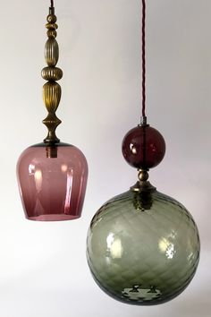 two different colored glass pendants hanging from strings on a white background, one is pink and the other is green