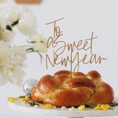 a cake that has some kind of bread on it with the words to be sweet new year