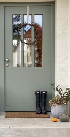 a pair of black boots sitting on the front step of a house next to a green door