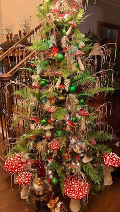 a christmas tree decorated with ornaments and greenery is shown in front of a stair case