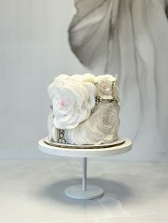 there is a white cake with flowers on the top and bottom, sitting on a stand