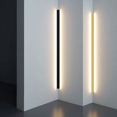 two lights that are next to each other in a room with white walls and black flooring