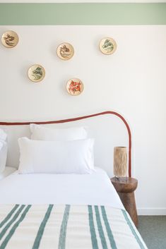 a bed with white sheets and pillows in a bedroom next to a wall with plates on it