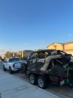 an atv on the back of a flatbed trailer parked next to a white pickup truck